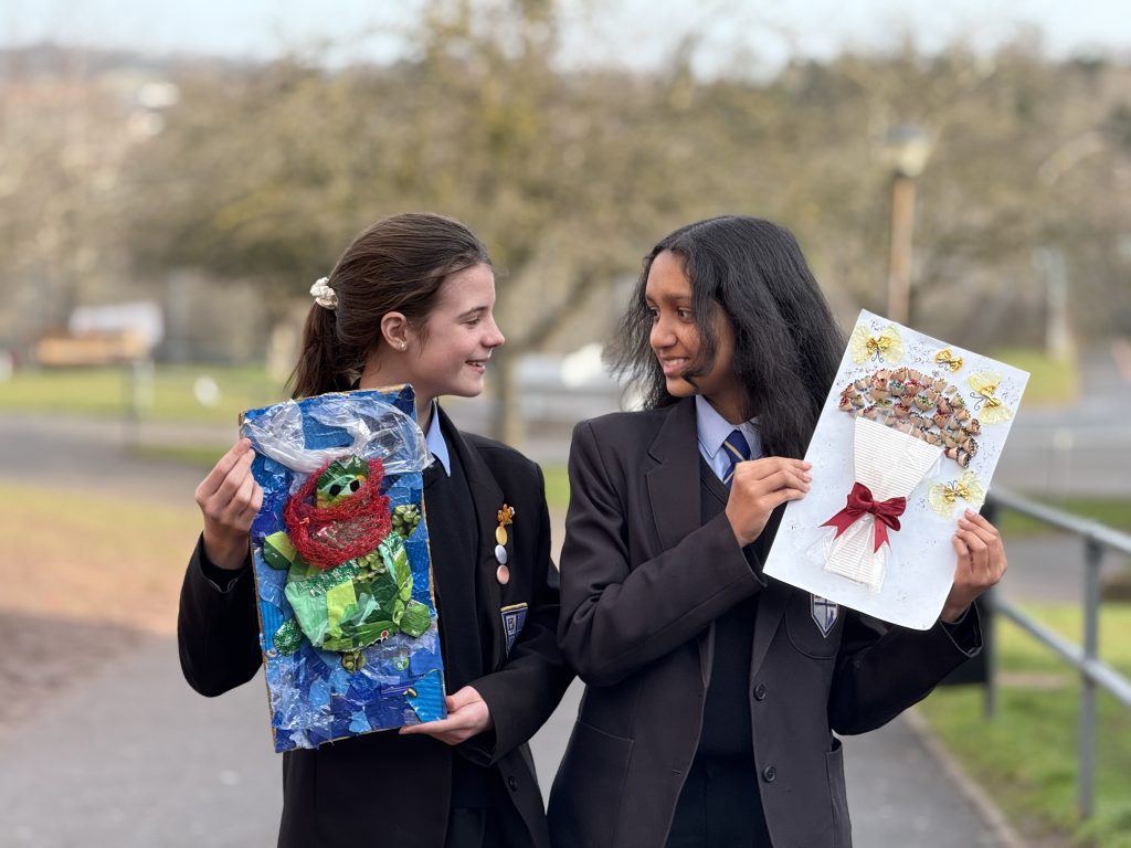 PSHE two smiling girls hold paintings at Bishop Perowne School