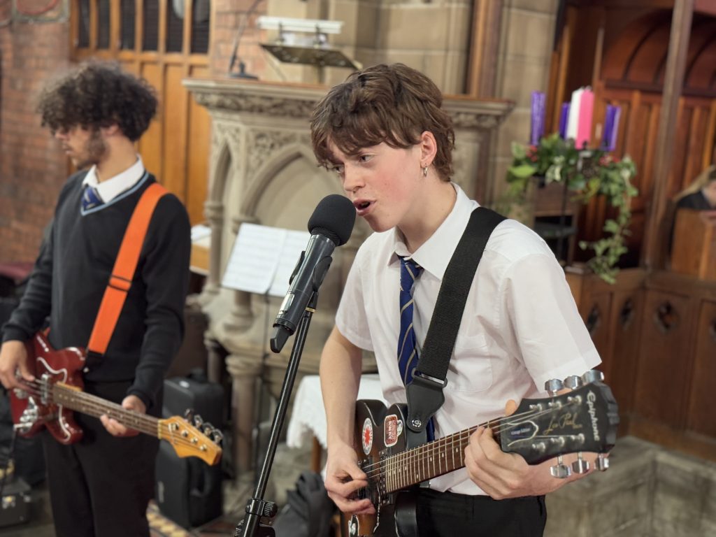 A boy is singing and playing the guitar in Music at Bishop Perowne